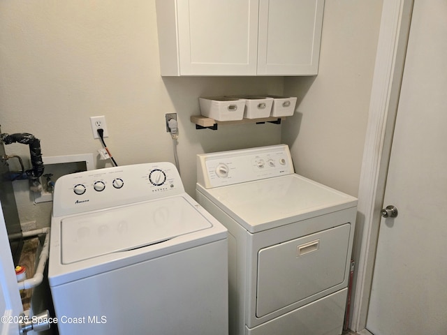 clothes washing area featuring washing machine and clothes dryer and cabinet space