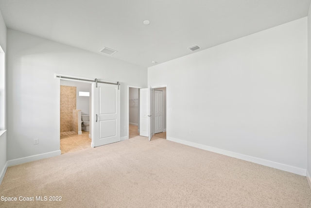 4280 Alamanda Key Dr, Melbourne, FL 32901 - unfurnished bedroom with baseboards, a walk in closet, a barn door, visible vents, and carpet