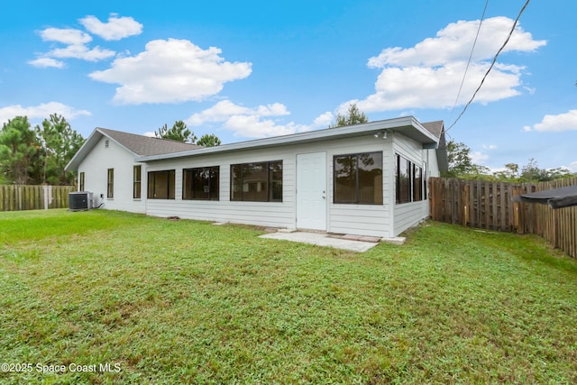 rear view of house featuring central AC, a fenced backyard, and a lawn