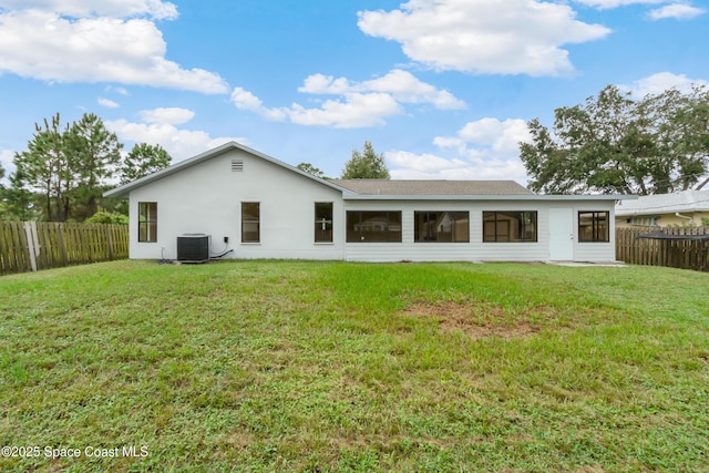 back of property featuring central air condition unit, a fenced backyard, and a lawn