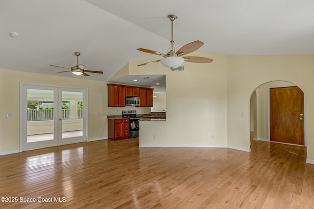 unfurnished living room with baseboards, a ceiling fan, light wood-style floors, visible vents, and arched walkways