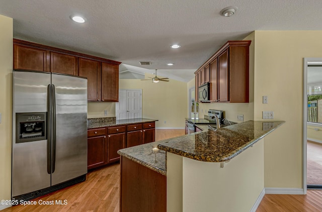 kitchen with a peninsula, visible vents, dark stone counters, stainless steel appliances, and light wood finished floors