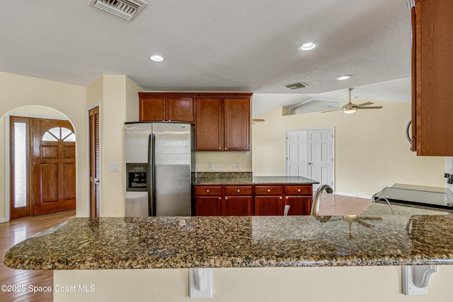 kitchen featuring stainless steel fridge with ice dispenser, visible vents, arched walkways, and wood finished floors