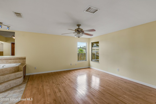 unfurnished room with visible vents, ceiling fan, light wood-type flooring, and baseboards