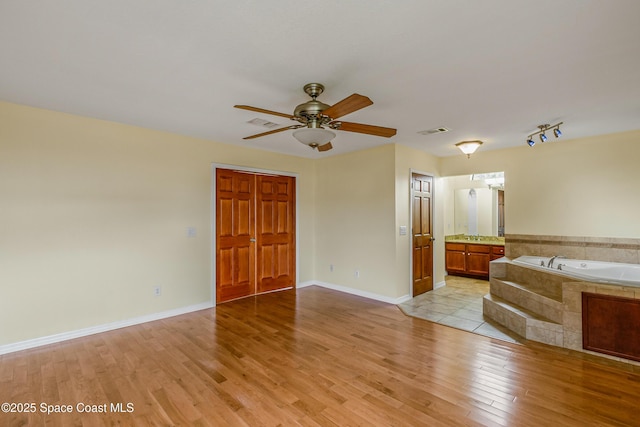 unfurnished bedroom with light wood-style flooring, baseboards, visible vents, and ensuite bath