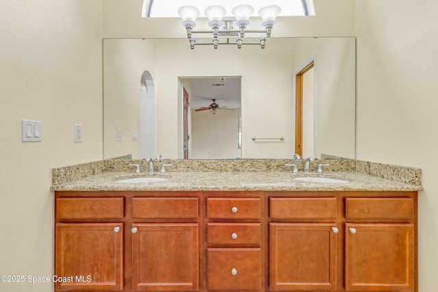bathroom featuring ceiling fan with notable chandelier, double vanity, and a sink