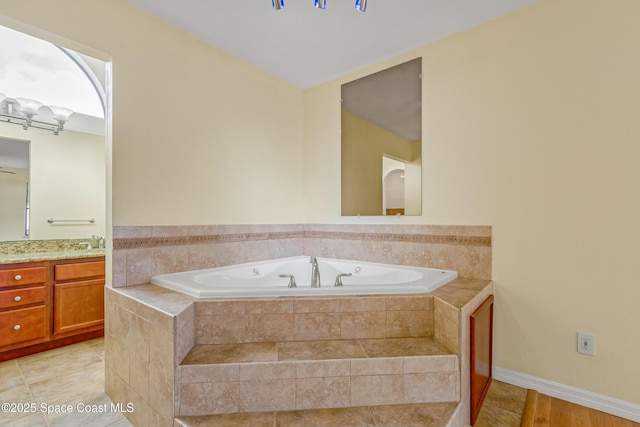 full bath with a whirlpool tub, a notable chandelier, and vanity