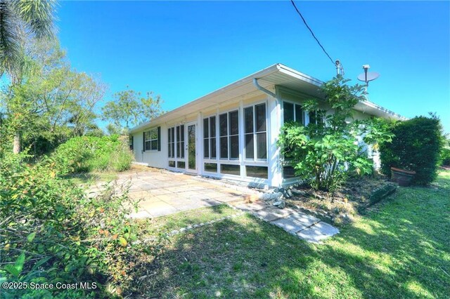 rear view of house featuring a sunroom, a patio, and a yard