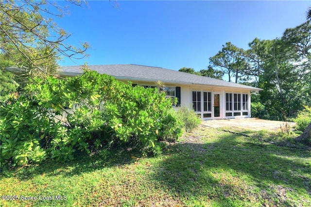 rear view of house featuring a sunroom and a lawn