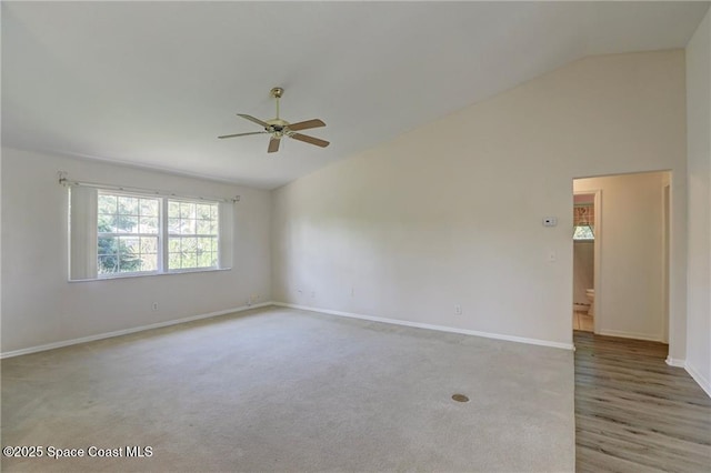 spare room with light colored carpet, ceiling fan, baseboards, and vaulted ceiling