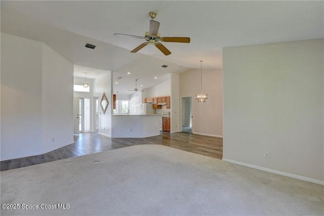 unfurnished living room featuring ceiling fan with notable chandelier, carpet flooring, baseboards, and visible vents