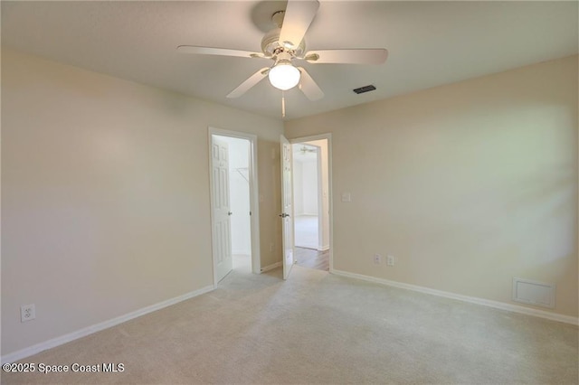 empty room featuring light colored carpet, baseboards, and a ceiling fan