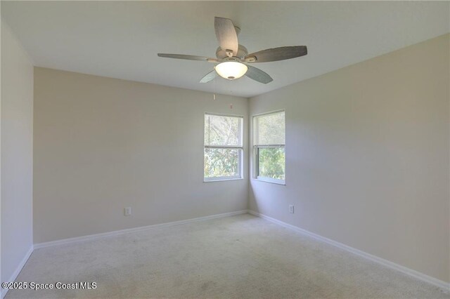 spare room featuring baseboards, a ceiling fan, and light carpet
