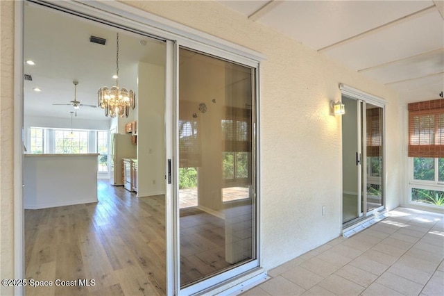 entrance to property featuring a balcony, stucco siding, and visible vents
