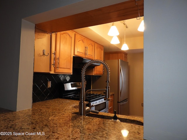 kitchen featuring stone countertops, freestanding refrigerator, and backsplash
