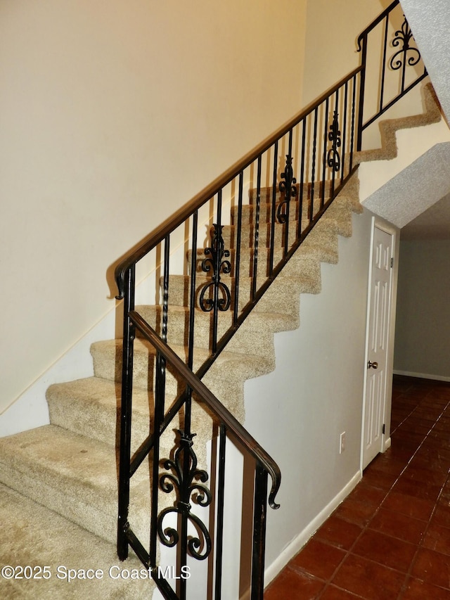 stairway with tile patterned floors and baseboards
