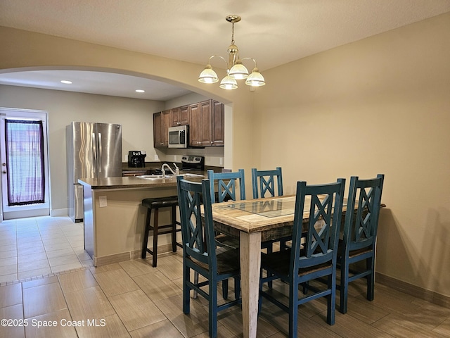 dining area featuring arched walkways, baseboards, an inviting chandelier, and recessed lighting