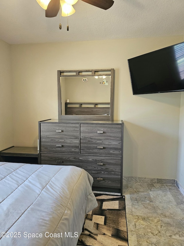 bedroom with baseboards, a ceiling fan, and stone finish flooring