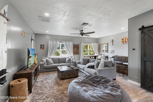 living area with recessed lighting, a barn door, visible vents, ceiling fan, and wood finished floors