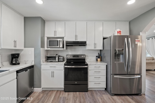 kitchen with light wood-style flooring, white cabinets, under cabinet range hood, and stainless steel appliances