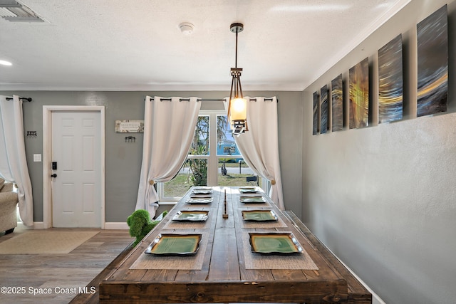 dining area featuring crown molding, wood finished floors, and visible vents
