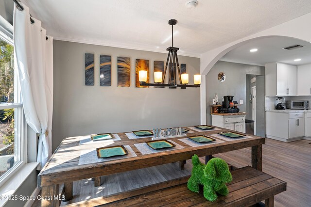 dining room with a toaster, light wood finished floors, ornamental molding, and visible vents