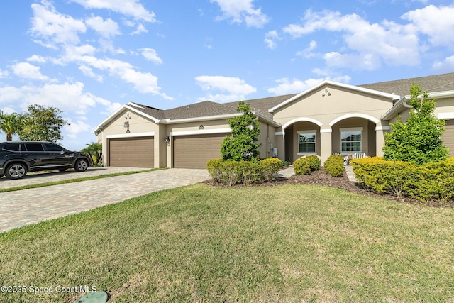 single story home with stucco siding, decorative driveway, a front lawn, and an attached garage