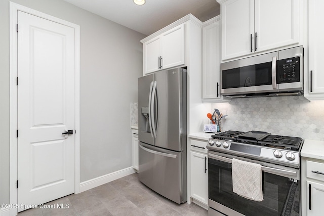 kitchen featuring decorative backsplash, stainless steel appliances, light countertops, white cabinets, and baseboards