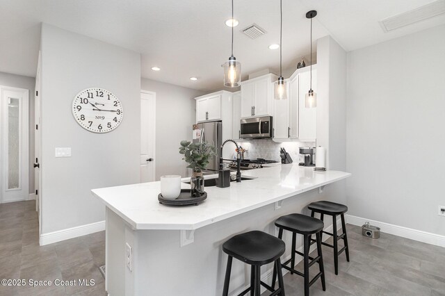 kitchen with a breakfast bar, visible vents, appliances with stainless steel finishes, and baseboards