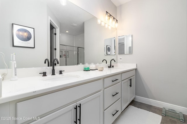 bathroom with double vanity, baseboards, a stall shower, and a sink