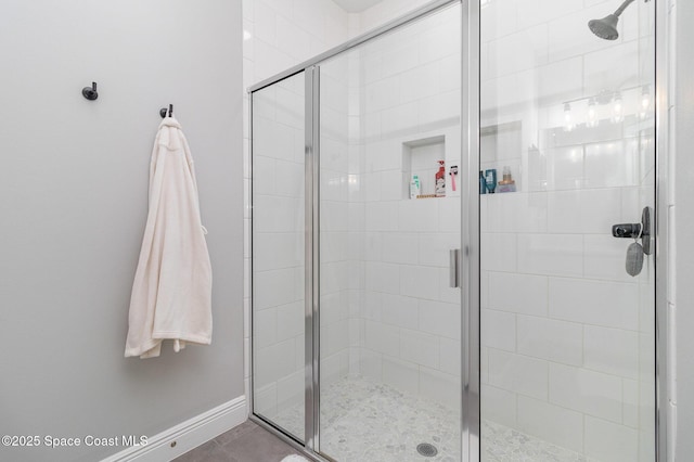 bathroom with a shower stall and baseboards