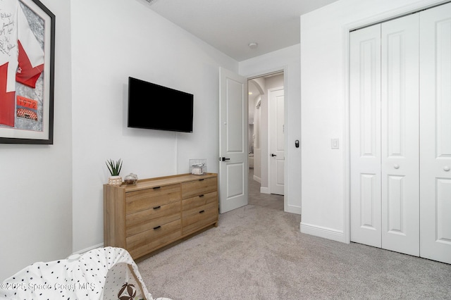 bedroom featuring baseboards, a closet, and light colored carpet