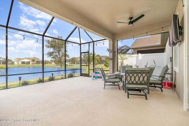 view of patio / terrace with a residential view, a water view, a ceiling fan, outdoor dining space, and a lanai