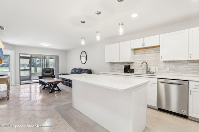 kitchen featuring open floor plan, stainless steel dishwasher, a sink, and decorative backsplash