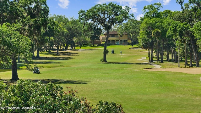 view of community with view of golf course and a yard