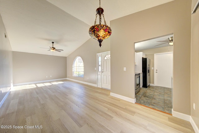 interior space featuring baseboards, a ceiling fan, light wood-style floors, and lofted ceiling