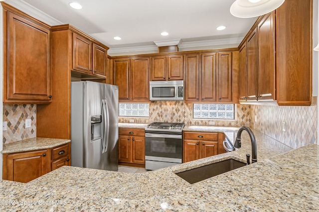 kitchen with a sink, tasteful backsplash, appliances with stainless steel finishes, and light stone countertops