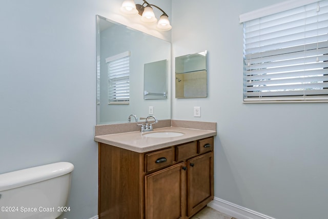 bathroom with toilet, vanity, and baseboards