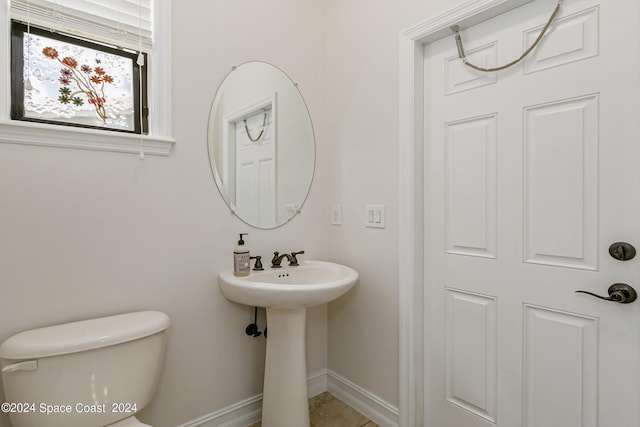 half bath featuring toilet, a sink, and baseboards