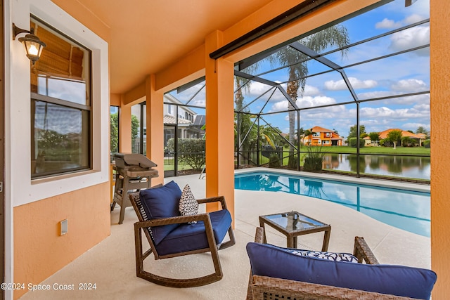 outdoor pool featuring a water view, grilling area, glass enclosure, and a patio area