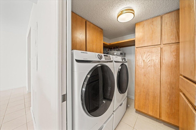 2101 Atlantic St Unit 531, Melbourne Beach, FL 32951 - clothes washing area featuring light tile patterned floors, a textured ceiling, washing machine and clothes dryer, and cabinet space