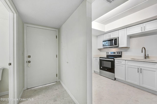 kitchen featuring white cabinets, light countertops, a sink, and appliances with stainless steel finishes