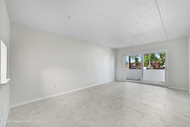 spare room featuring a textured ceiling and baseboards