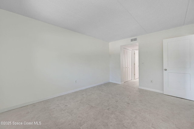 empty room featuring visible vents, baseboards, and a textured ceiling