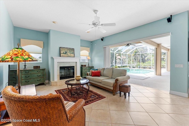 living room featuring a sunroom, light tile patterned flooring, a high end fireplace, and a ceiling fan