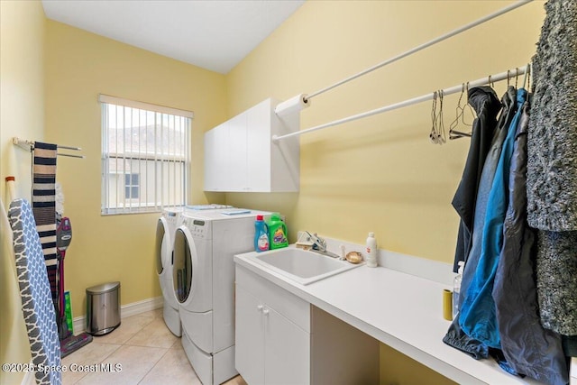 laundry area featuring baseboards, light tile patterned floors, independent washer and dryer, cabinet space, and a sink