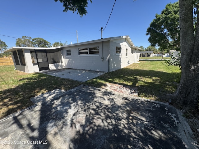 back of house with a yard, concrete block siding, a sunroom, and a patio area