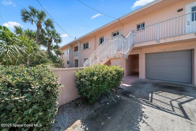 1700 Atlantic St Unit 12, Melbourne Beach, FL 32951 - view of property featuring an attached garage, stairs, fence, and aphalt driveway