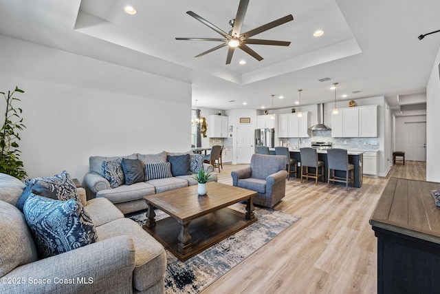2631 Pinwherry St NW, Palm Bay, FL 32907 - living room featuring a tray ceiling, ceiling fan with notable chandelier, light wood finished floors, and recessed lighting