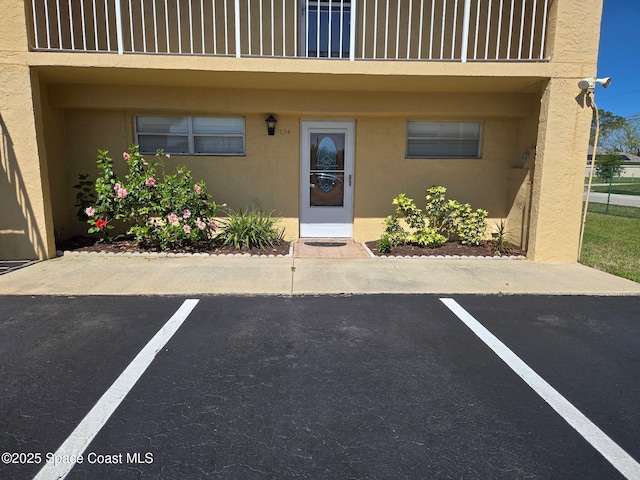 view of exterior entry featuring uncovered parking and stucco siding